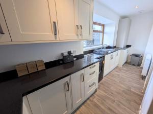 a kitchen with white cabinets and a black counter top at 2 Bedroom Townhouse with Seaview on the NC500 Wick in Wick