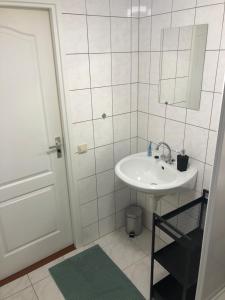 a white bathroom with a sink and a mirror at Vrijstaand Chalet in Bospark in Hattemerbroek