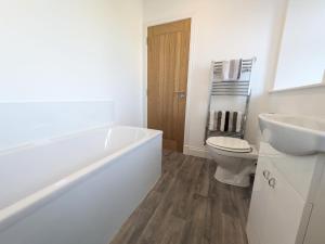 a bathroom with a tub and a toilet and a sink at 2 Bedroom Townhouse with Seaview on the NC500 Wick in Wick