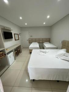 a hotel room with two beds and a television at Pousada Augusta in Penha