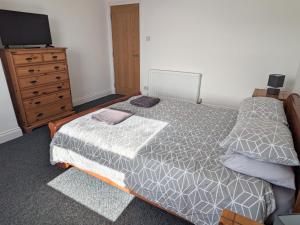 a bedroom with a bed and a dresser and a television at 2 Bedroom Townhouse with Seaview on the NC500 Wick in Wick