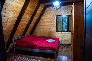 Dormitorio pequeño con cama roja en el ático en Cabana Arunia, 