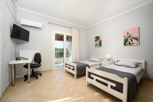 a bedroom with two beds and a desk and a computer at Xenia's Apartments in Alepou in Corfu