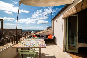 einen Balkon mit einem Tisch, Stühlen und einem Sofa in der Unterkunft Scala 70° Attico Esclusivo in Caltagirone