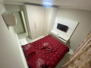 um pequeno quarto com uma cama vermelha e uma televisão em Apartamento AV. Brasil Frente Sh. Atlântico em Balneário Camboriú
