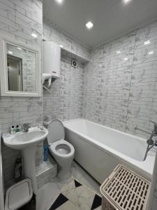 a bathroom with a white tub and a toilet and a sink at Байзак- батыра 187 in Taraz