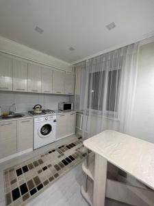 a kitchen with white cabinets and a stove and a table at Байзак- батыра 187 in Taraz