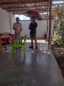 a man holding an umbrella next to a green chair at Nomads Club in Nazca