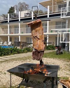 a person cooking food on a grill in front of a building at Apart Hotel La Giraldilla in Chascomús