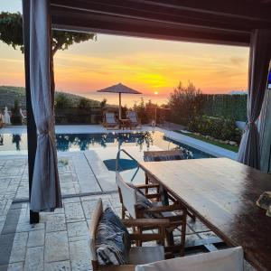 a patio with a wooden table and a swimming pool at Stergiou Luxury Apartments with shared pool in Anavissos