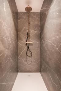 La salle de bains est pourvue d'une douche et d'un mur en marbre. dans l'établissement Ter Heyde Walle, à Koekelare