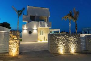 a white house with palm trees and lights at Vela Bianca Marzamemi in Marzamemi