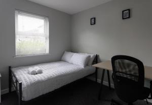 a small bedroom with a bed and a desk and a chair at Apartment 4 Oak Villa in Belfast