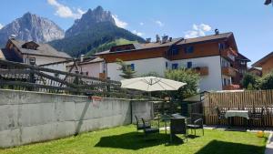 - une table, des chaises et un parasol dans la cour dans l'établissement Casa Il Giardino, à Pozza di Fassa