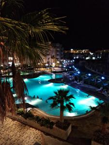 a large swimming pool at night with palm trees at Super appartement avec 5 piscines en résidence in Monastir