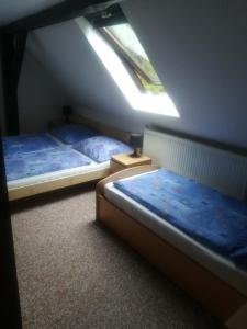 2 łóżka w małym pokoju z oknem w obiekcie Chalupa pod sjezdovkou w mieście Chvaleč