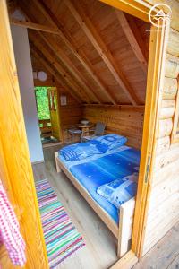 Ce lit se trouve dans une cabane en rondins dotée d'une table. dans l'établissement Rafting Center "TARA-RAFT", à Bastasi