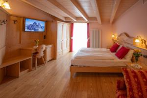 1 dormitorio con 1 cama, escritorio y TV en B&B Casa Agostini, en Fai della Paganella