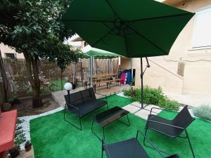 a patio with a green lawn with chairs and an umbrella at Casa Clara Oristano centro con giardino in Oristano