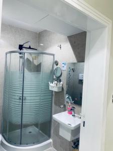 a bathroom with a glass shower and a sink at أزهار النرجس للشقق الفندقية in Umm al Khashab