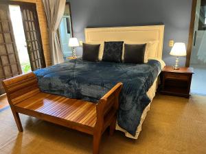 a bedroom with a large bed and a wooden bench at Pousada Dona Bendita in Monte Verde