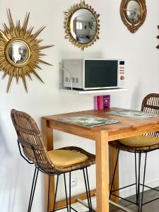 een tafel met stoelen, een magnetron en spiegels bij Les Pinsons studio in La Ciotat