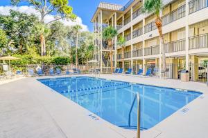 a swimming pool in front of a building with palm trees at Sea Side Villas 244 in Hilton Head Island
