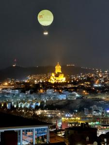 a hot air balloon flying over a city at night at Check Point Hotel in Tbilisi City