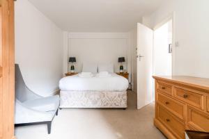 a white bedroom with a bed and a chair at Gorgeous Putney Flat in London