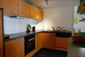 a kitchen with orange cabinets and a black dishwasher at Drosera cabane et roulotte in La Chaux-du-Milieu