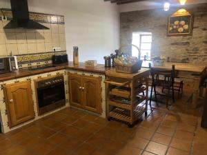 une cuisine avec des placards en bois et une table avec un comptoir dans l'établissement Casa da Oliveira, à La Corogne