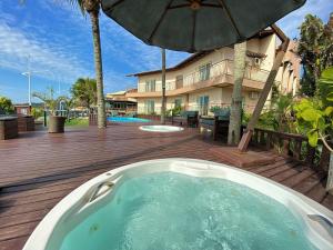 a hot tub on a wooden deck with an umbrella at Morada do Mar Hotel in Bombinhas