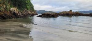 einen Strand mit Felsen im Wasser an einem wolkigen Tag in der Unterkunft Casa da Oliveira in Cariño