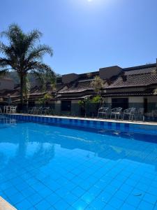 uma piscina azul com cadeiras e uma palmeira em Pousada do Sol em Penedo