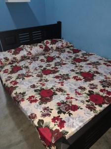 a bed with a floral comforter on it at MSV VILLA RÉSIDENCE HOME in Batticaloa