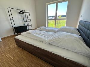 ein großes Bett in einem Zimmer mit einem großen Fenster in der Unterkunft EBM-Apartments Altenmünster mit Wallbox in Altenmünster
