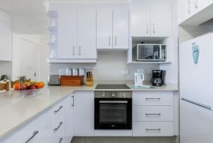 una cucina bianca con armadietti e elettrodomestici bianchi di Laguna La Crete 9 a Uvongo Beach