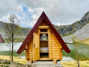 a tiny house with a pitched roof on a lake at Rural Household MINIĆ - Kapetanovo jezero in Kolašin