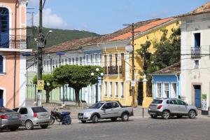 eine Stadtstraße mit Autos, die vor den Gebäuden geparkt sind in der Unterkunft Conforto e bom gosto no Recôncavo da Bahia. in São Félix