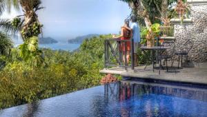 a swimming pool with a balcony overlooking the water at Hotel Villa Caletas in Jacó