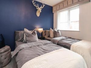 two beds in a room with blue walls at Damson Cottage in Poulton le Fylde