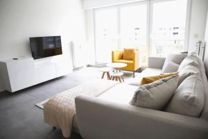 a living room with a white couch and a tv at Charming modern 2 BR apartment in Alzingen