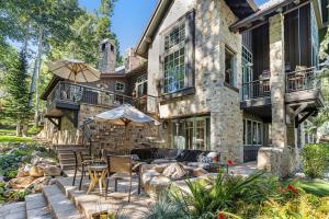 a stone house with a patio with chairs and an umbrella at Chateau at Elk Spring in Edwards