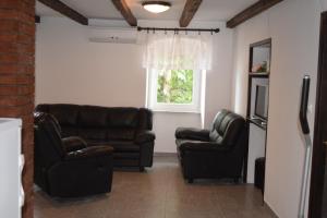 - un salon avec deux fauteuils en cuir et une télévision dans l'établissement Apartman Cergolj, à Lovran