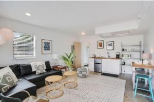 ein Wohnzimmer mit einem schwarzen Sofa und einer Küche in der Unterkunft River Breeze Quiet & Modern Black Pearl Apartment in New Orleans
