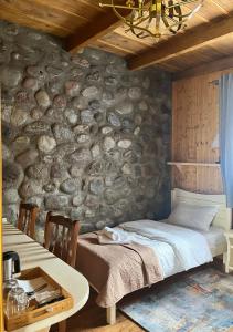 1 dormitorio con pared de piedra, cama y mesa en Inn Harmony, en Kazbegi
