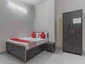 a bedroom with a bed with red pillows and a cabinet at OYO Flagship A Hospitality in Lucknow