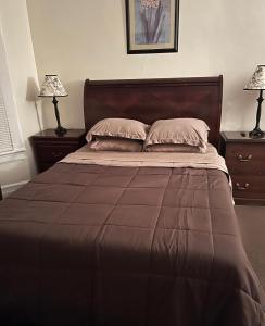 ein Schlafzimmer mit einem Bett mit zwei Nachttischen und zwei Lampen in der Unterkunft Victorian Palace- Mahogany Room in East Orange