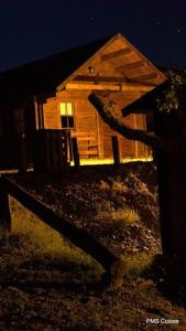 una pequeña casa de madera por la noche con una valla en Monte do Azibo Glamping, en Podence