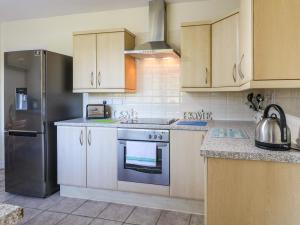 a kitchen with white cabinets and a stainless steel refrigerator at Hideaway in Alfreton